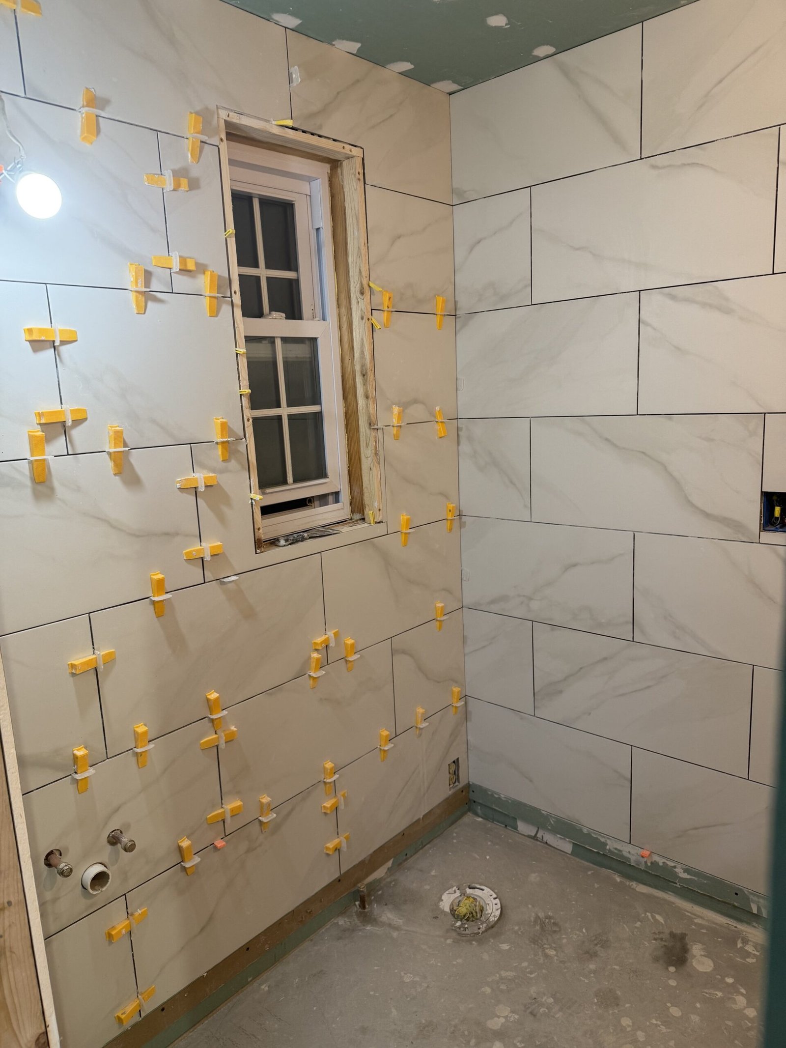 Large-format wall tile installation beginning in a Boxford bathroom