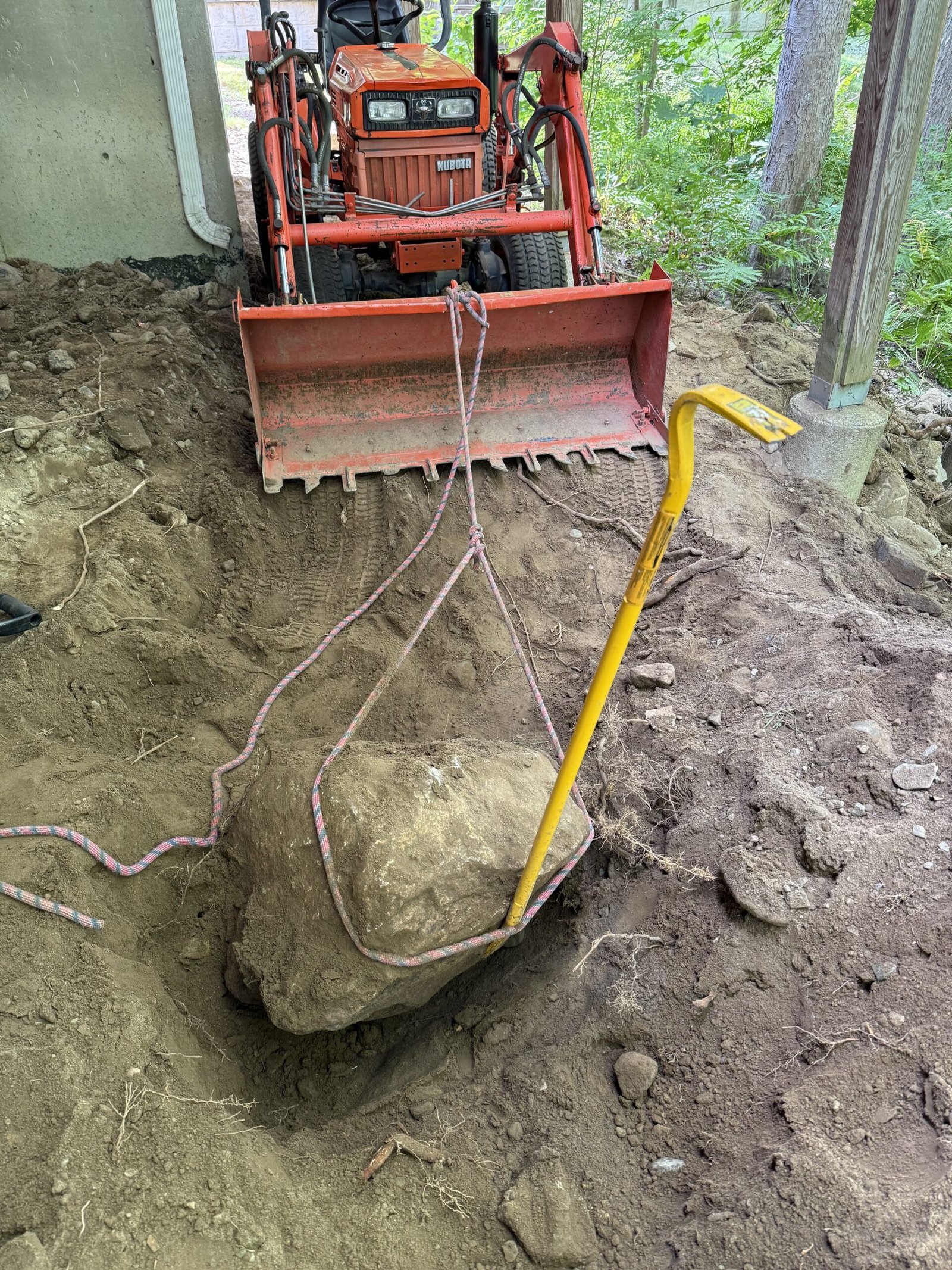 Excavator working around exposed boulder and rough excavation in Dover Massachusetts