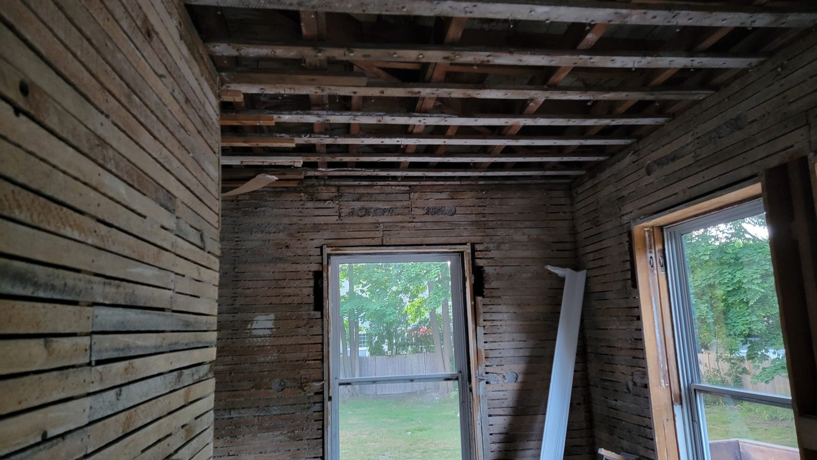 Wide view of a Marblehead office opened to wood lath and ceiling framing during demolition