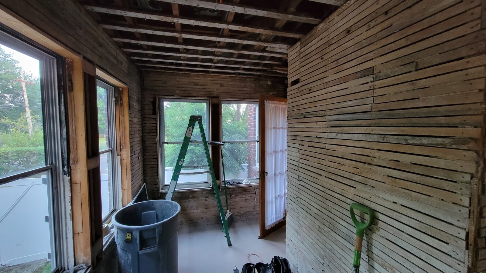 Long view of the stripped office with exposed lath windows and ceiling framing in Marblehead Massachusetts