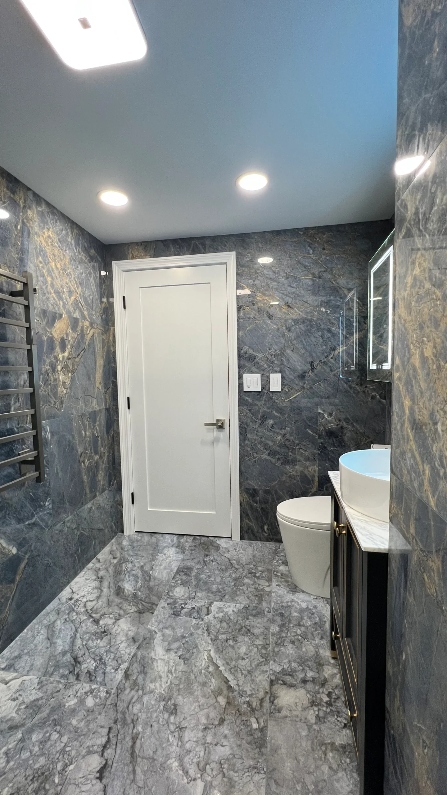 Finished Salem bathroom with stone-pattern tile glass enclosure vanity and white door