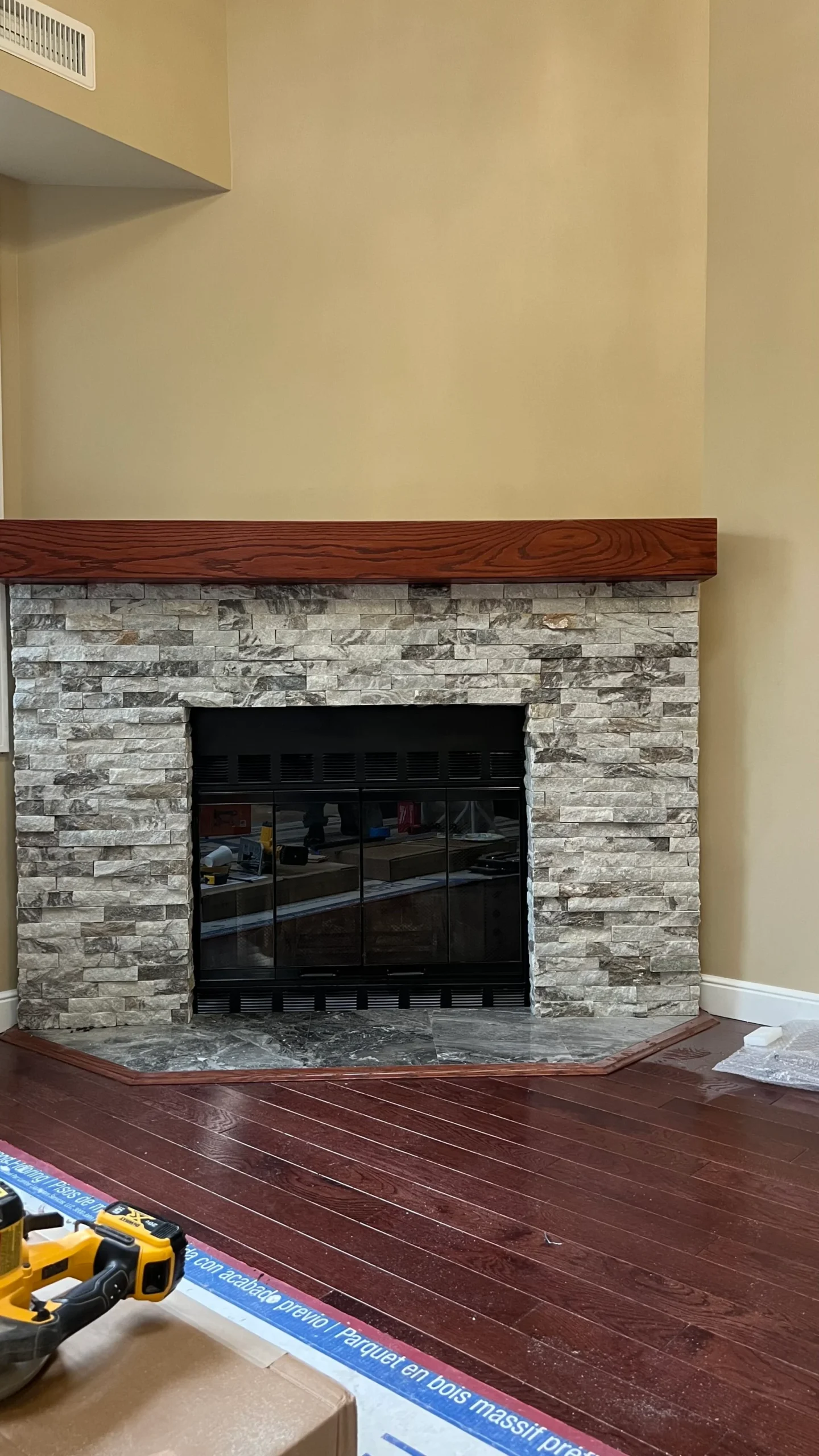 Completed fireplace wall with stone surround wood mantel and hardwood flooring in Salem Massachusetts