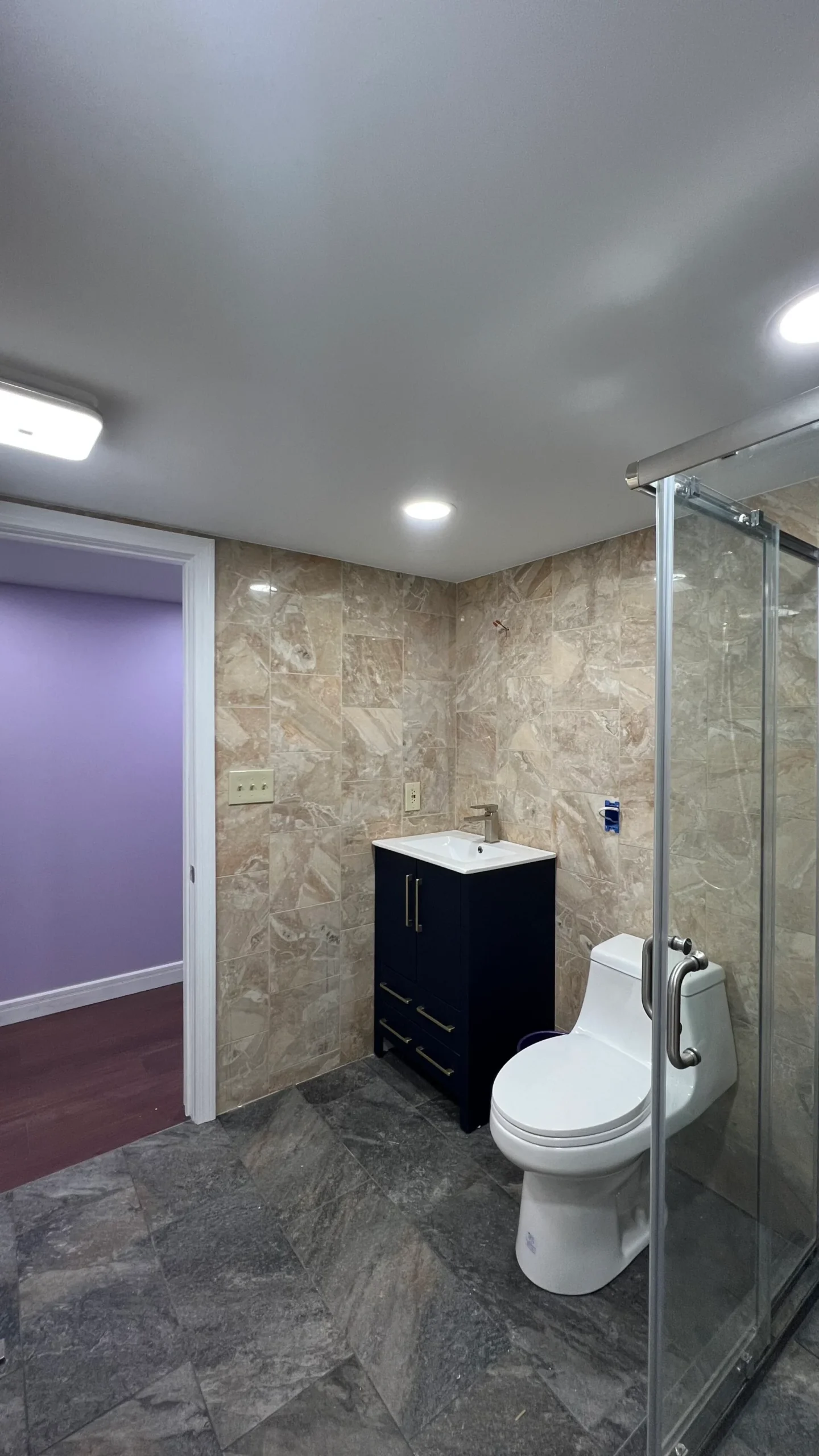 Finished Salem bathroom with tiled walls glass shower dark vanity and recessed lighting