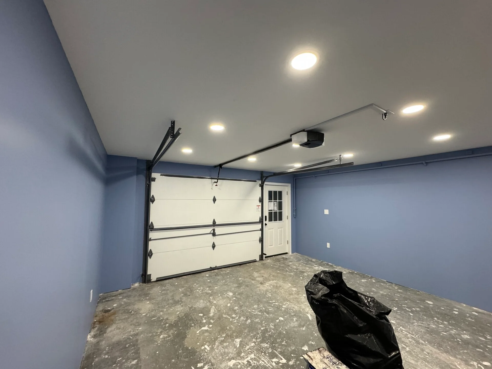 Garage renovation in progress with unfinished floor and newly painted walls in Salem Massachusetts