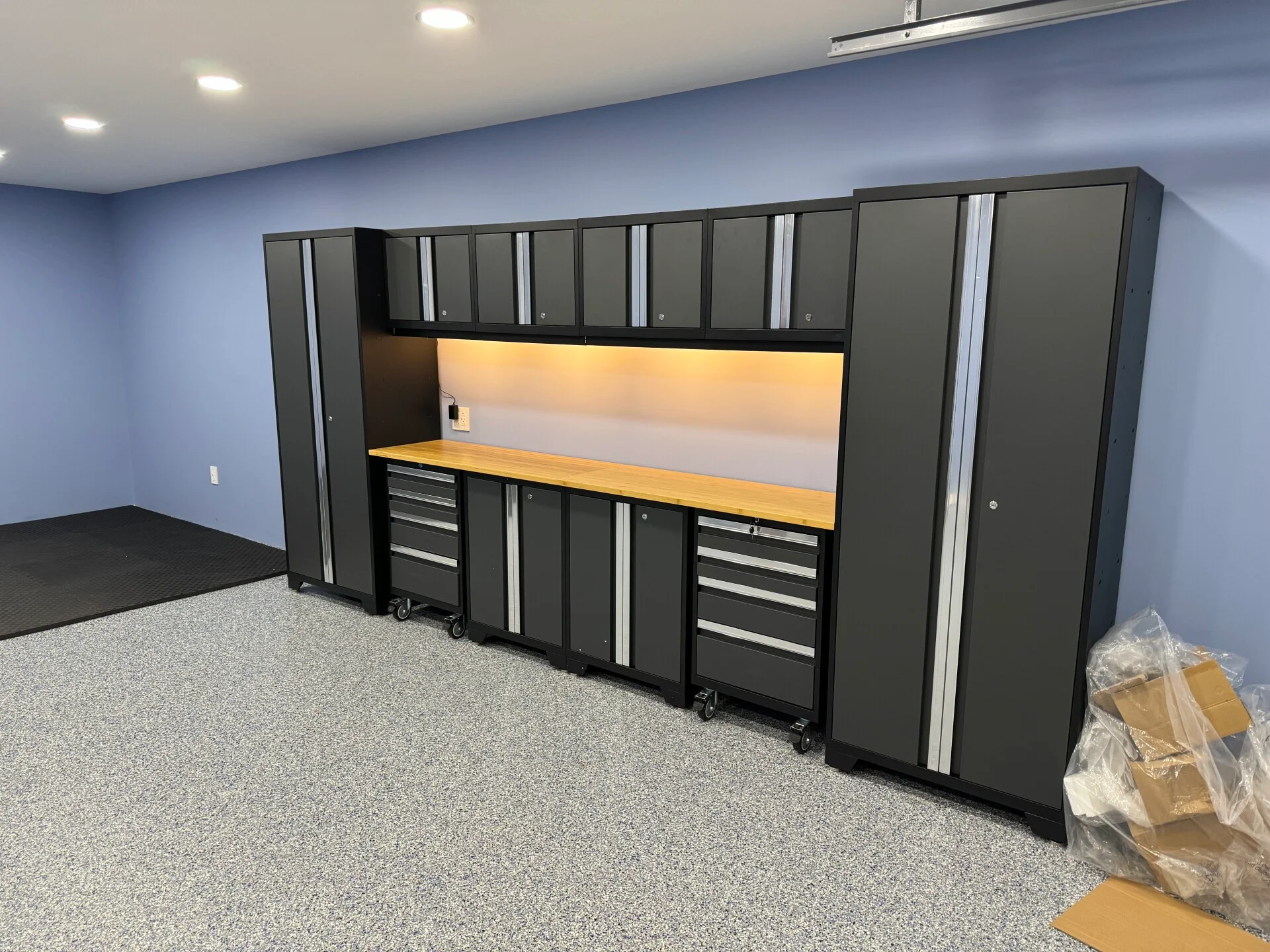 Completed Salem garage with storage cabinets illuminated workbench recessed lighting and finished flooring