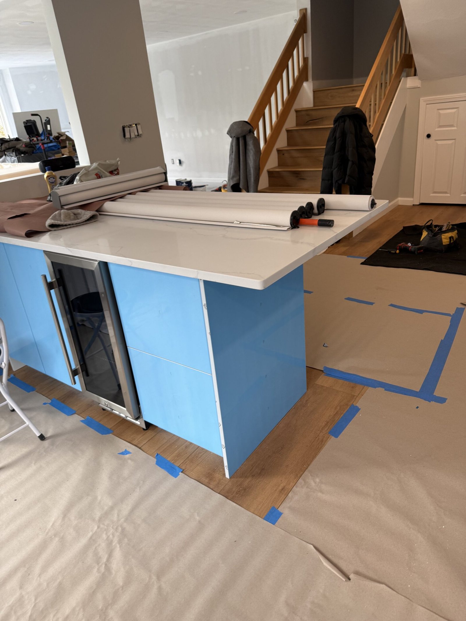 Close view of a glossy white kitchen island under blue protective film with a white counter in Salem Massachusetts