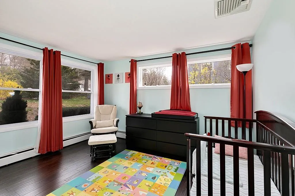 Professionally staged upper room with hardwood flooring windows and railing in a renovated Saugus home