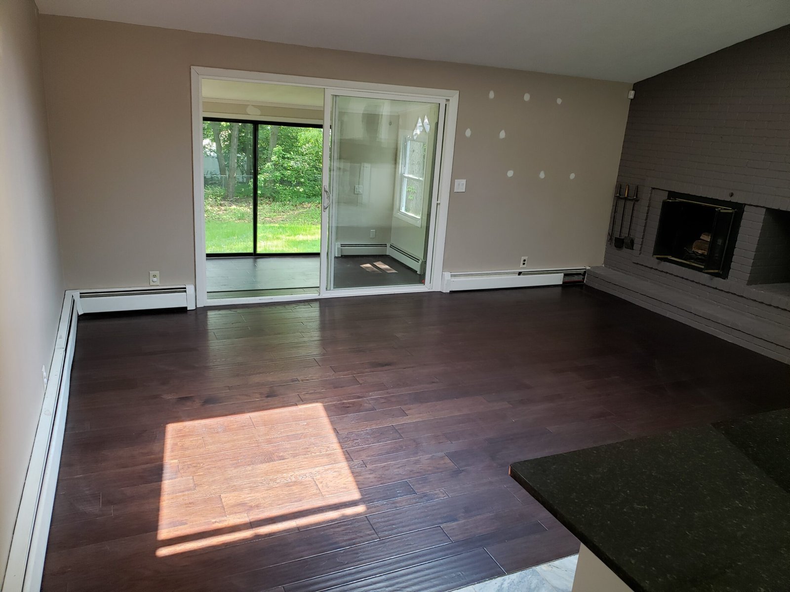 Completed open living room with fireplace sliding doors and engineered hardwood flooring in Saugus