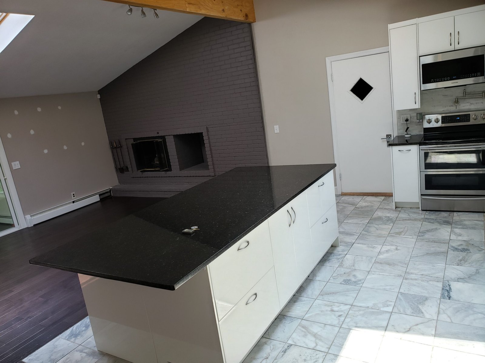 Completed Saugus kitchen showing dark counters white cabinetry island and open living-room connection