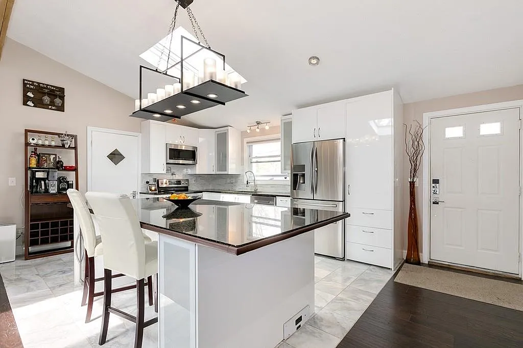 Wide staged view of the completed white kitchen island and dining area in Saugus Massachusetts