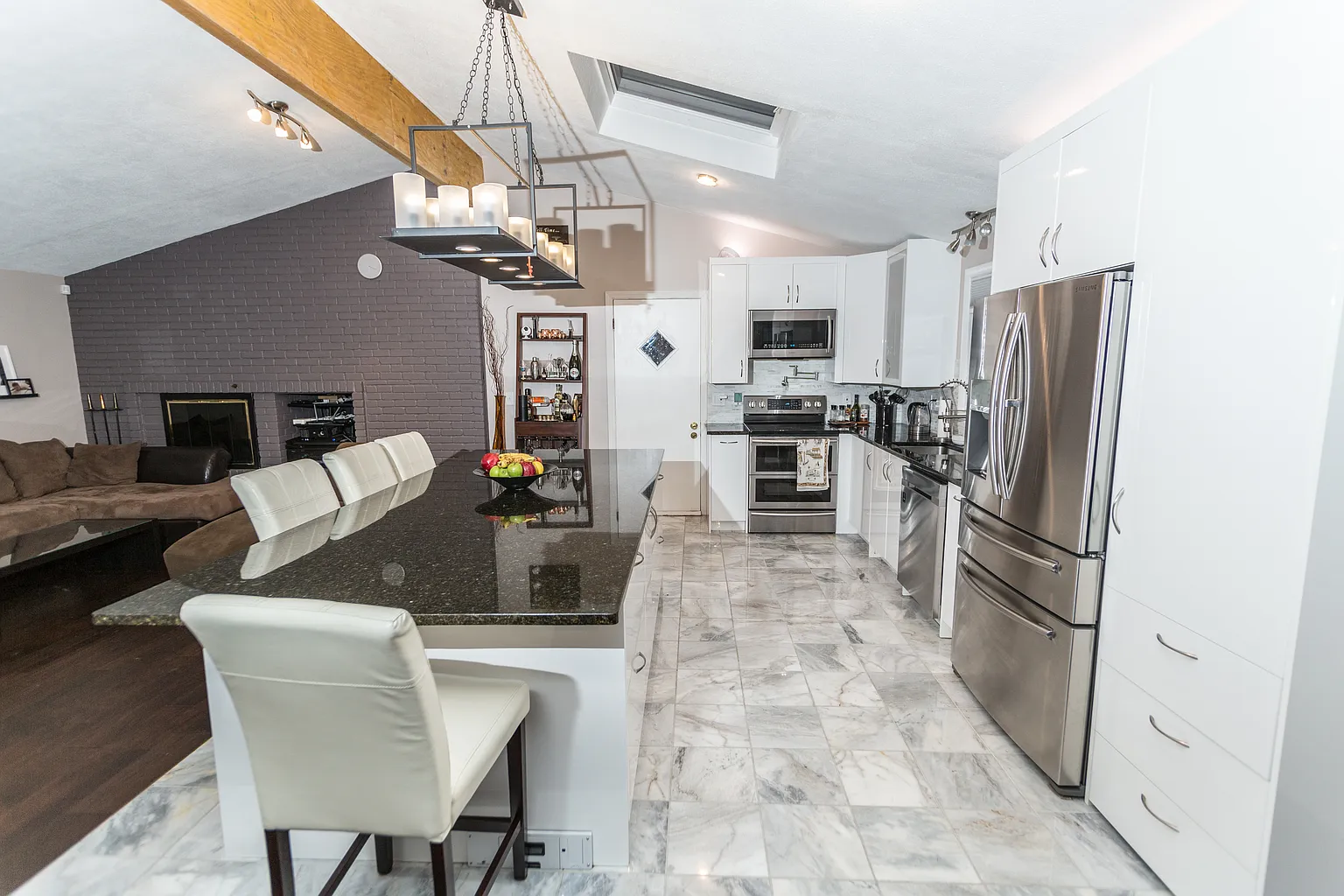 Staged open-plan Saugus living area showing the exposed LVL beam kitchen and fireplace