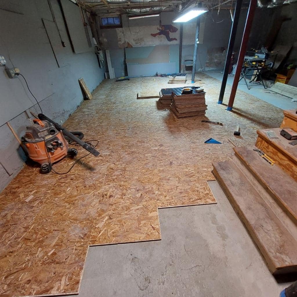 Elevated wood subfloor panels being installed over the basement slab in Marblehead Massachusetts