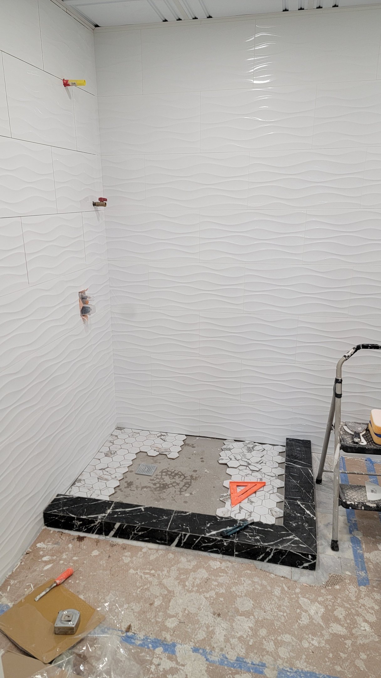 Finished wave-pattern wall tile and mosaic floor during a Marblehead bathroom build